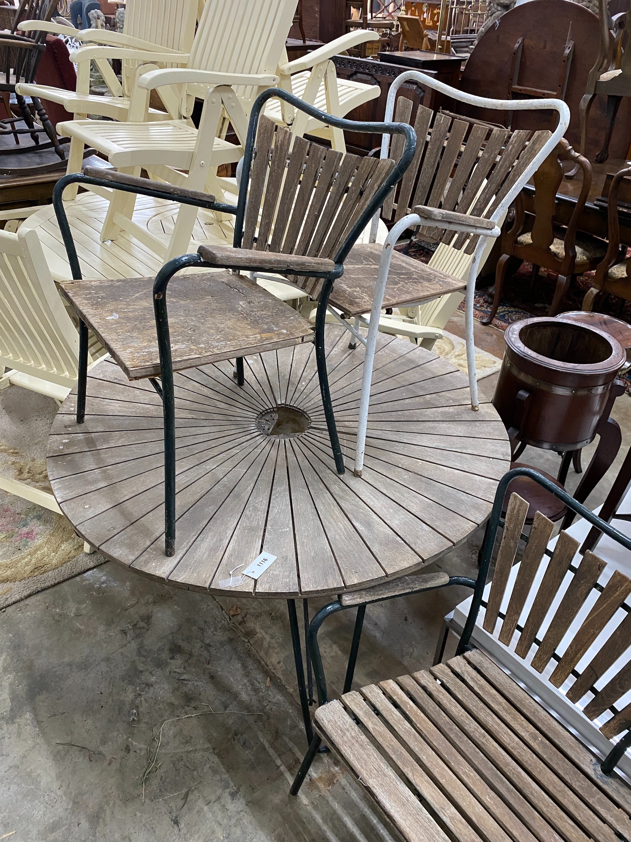 A 1950's slatted wood and wrought iron circular garden table, diameter 180cm, height 62cm, together with two elbow chairs and a bench seat